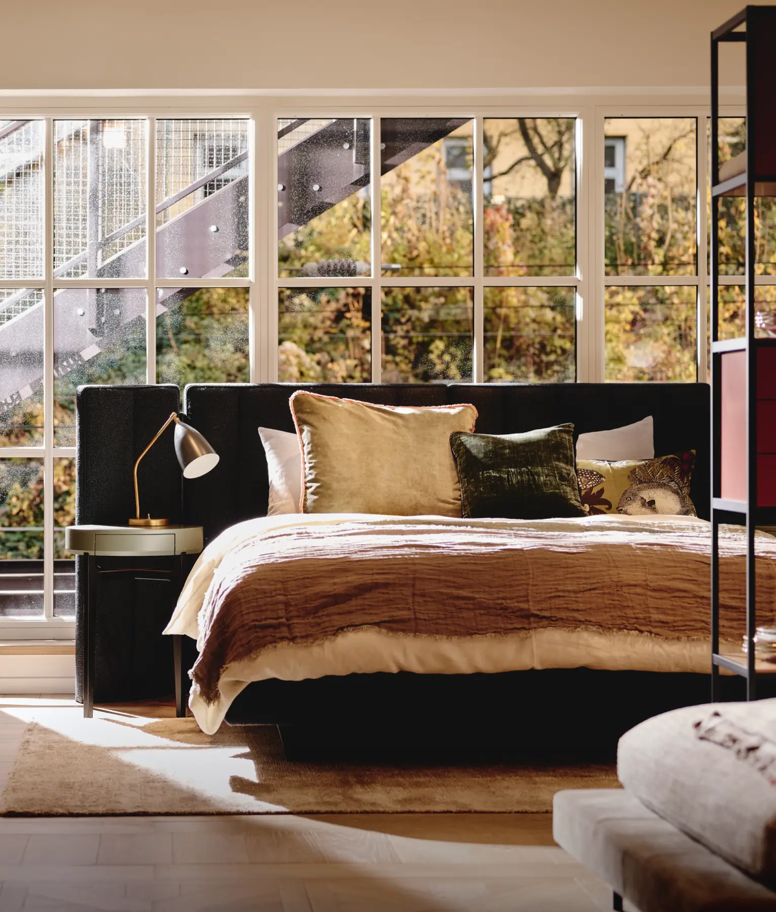 ein Bett mit Kissen und einer Lampe in einem Raum mit Fenstern